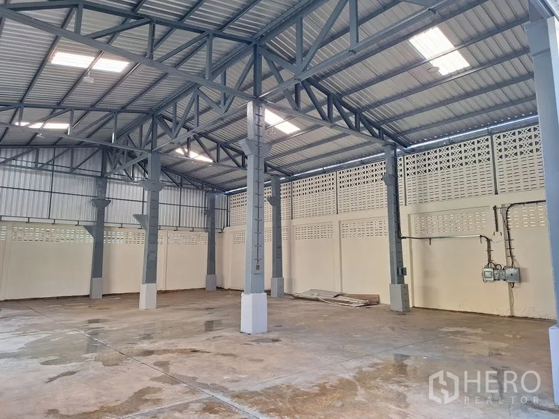 Warehouse for rent in Rat Burana, Bangkok - High-ceiling warehouse space with steel columns, skylights, and ventilated block walls.