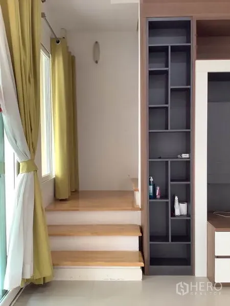 联排别墅 出租或出售在Wang Thonglang, Bangkok - 短木楼梯旁是带绿色窗帘的高窗与竖向收纳架。