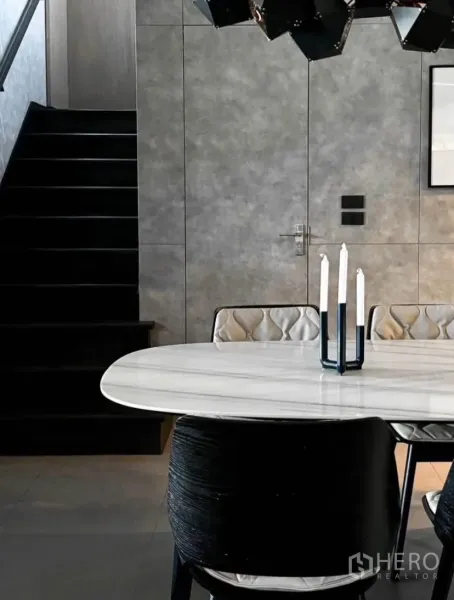 Townhouse for rent or sale in Bang Phli, Samut Prakan - Sleek dining area with an oval marble table, designer chairs and a staircase against matte grey walls.