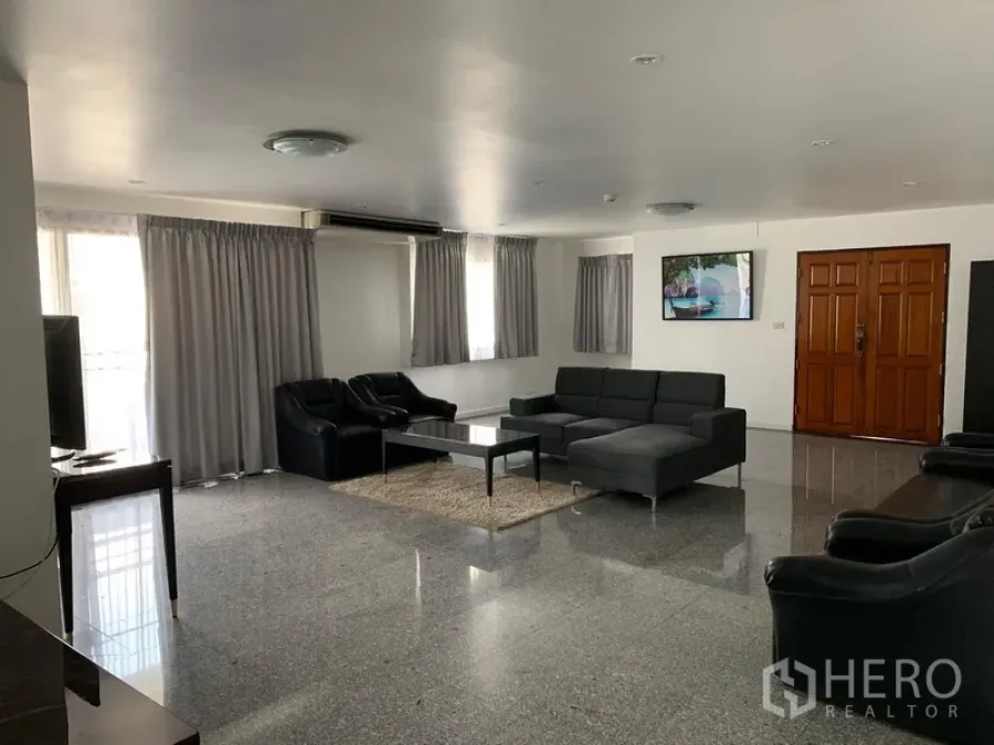 公寓 出租或出售在Watthana, Bangkok - 大客厅，转角沙发与单人沙发，亮面地砖地面。