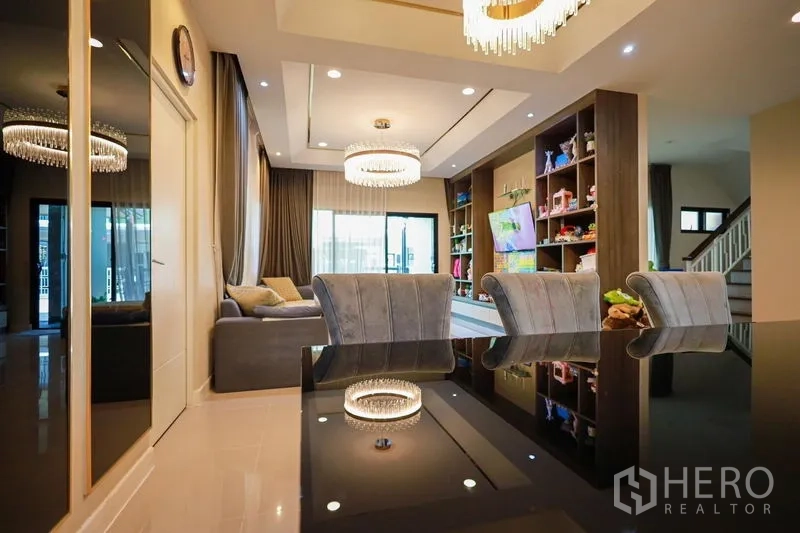 Detached House for rent or sale in Lam Luk Ka, Pathum Thani - Dining area connected to living room, crystal chandelier and feature shelving.