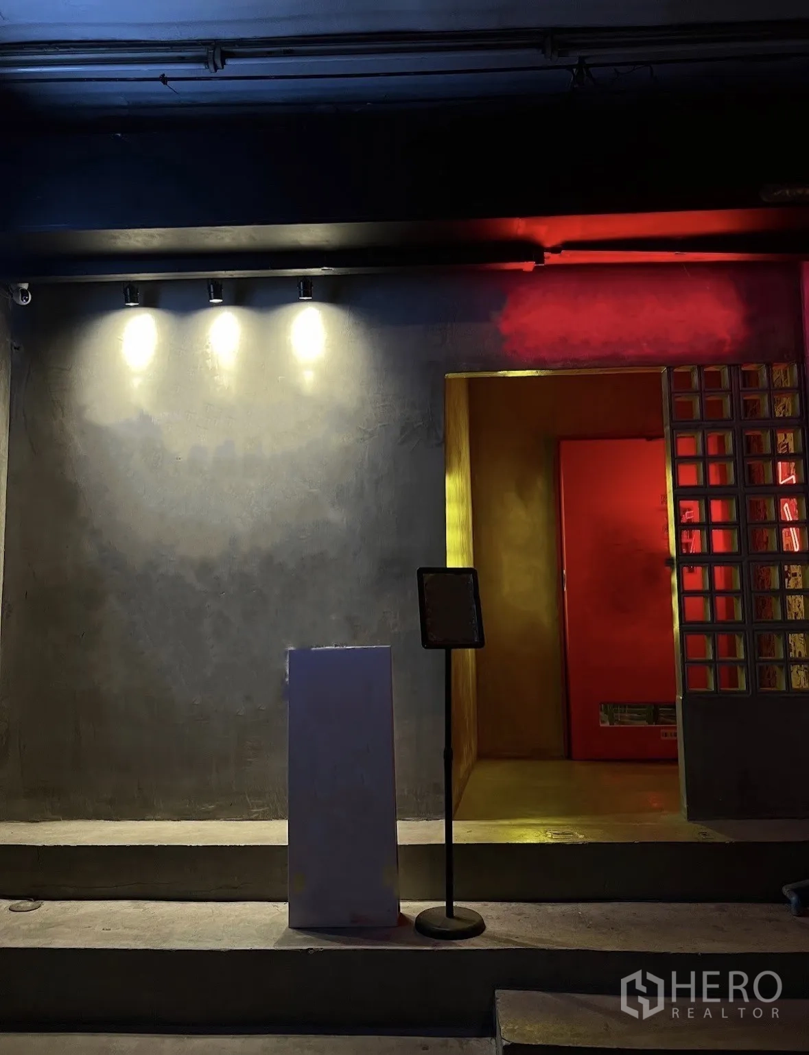 店屋 出租在Watthana, Bangkok - 夜景店面，混凝土外墙与明亮的红色入口。