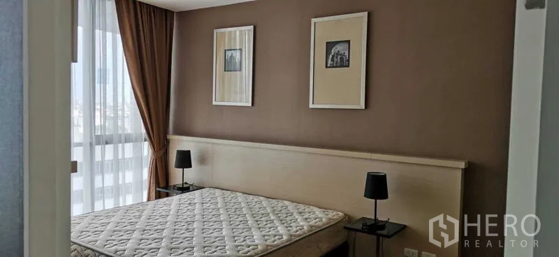 公寓 出租在Watthana, Bangkok - 温馨卧室，配大床、床头灯与墙面装饰画。