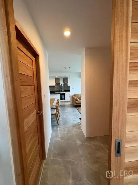 公寓 出租或出售 - 带木门的走廊，通向开放式客餐厅与厨房的现代公寓。