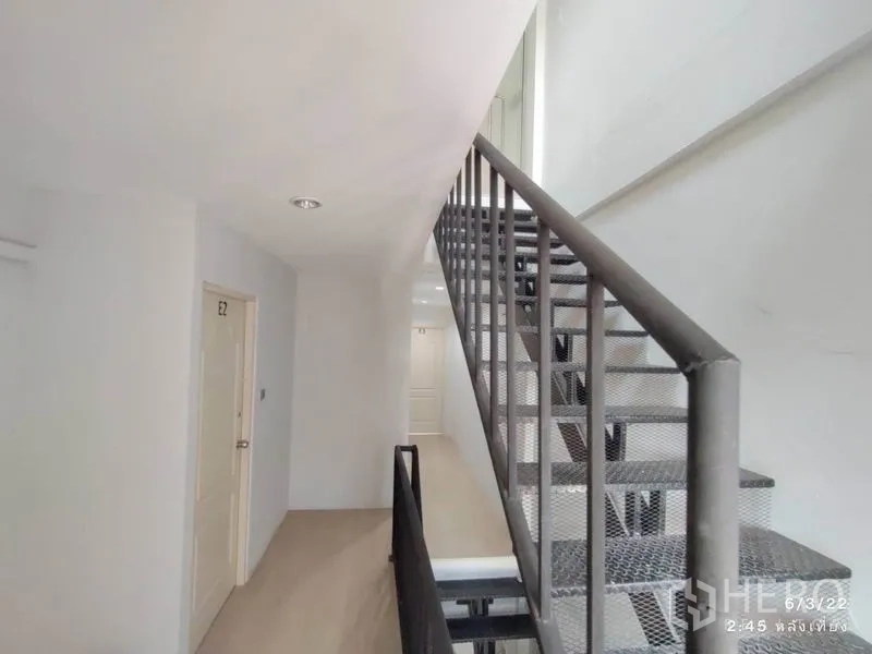 零售空间 出租在Phaya Thai, Bangkok - 金属楼梯旁的走廊，通往E2房门的简约白色空间。