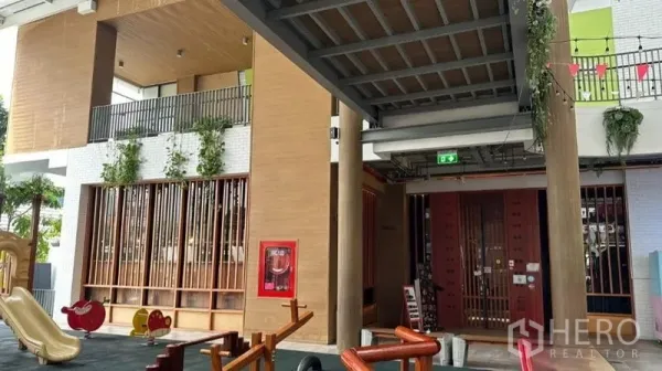 零售空间 出租 - 带顶走道与木质装饰入口，垂挂绿植，旁设儿童游乐区