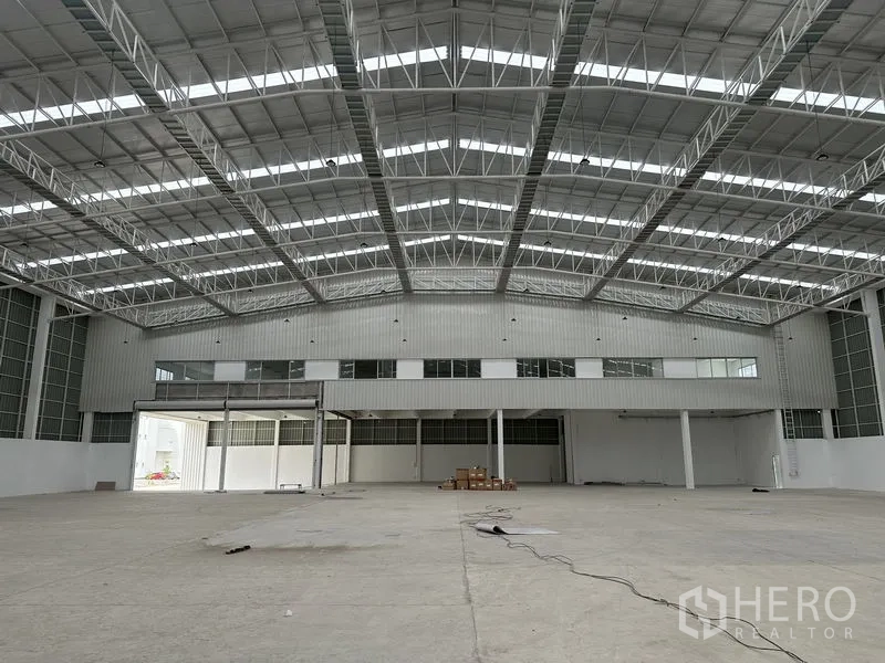 Factory for rent in Pathum Thani - Factory interior facing mezzanine offices and a large roller shutter door.