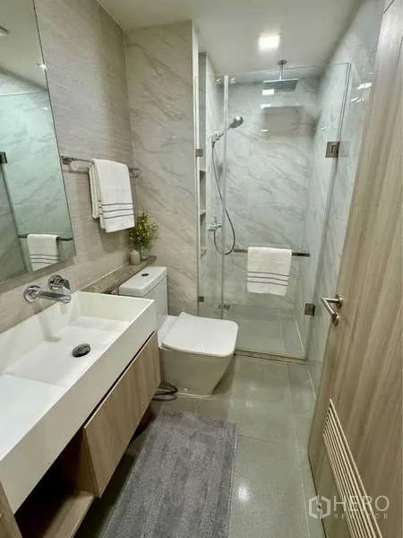 คอนโด ให้เช่าในWatthana, Bangkok - ห้องน้ำสมัยใหม่ ผนังลายหินอ่อน ฝักบัวกระจก อ่างล้างหน้าลอย และโถสุขภัณฑ์แขวนผนัง