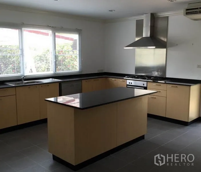 独立式住宅 出租在Bang Phli, Samut Prakan - 现代U形厨房，黑色花岗岩台面，带中岛、烤箱与不锈钢抽油烟机。