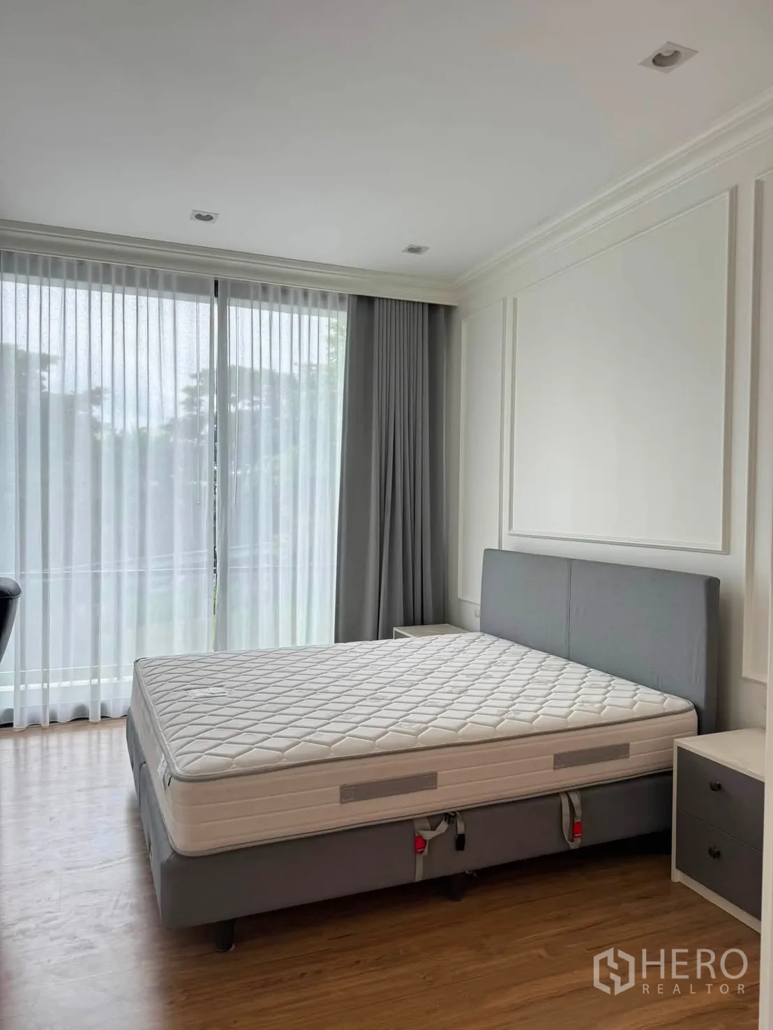 Townhouse for rent in Lat Phrao, Bangkok - Bedroom with sliding glass doors to a balcony and soft drapes.