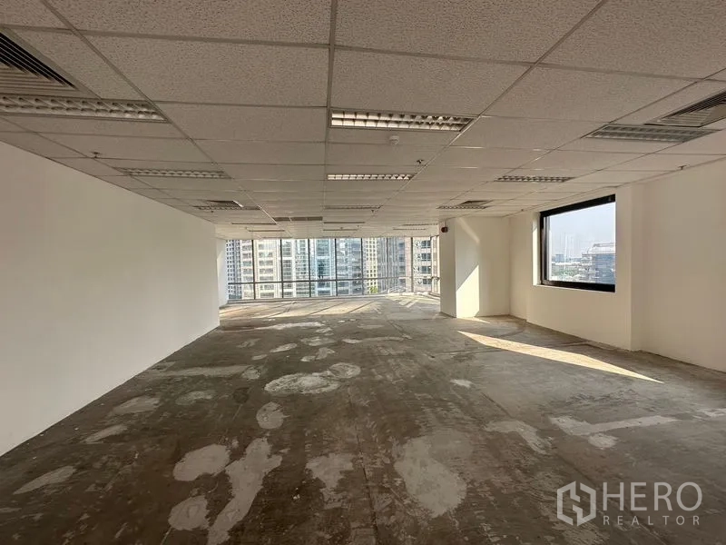 Office Space for rent - Shell-condition office interior with grid ceiling, air vents and wide windows framing downtown towers.