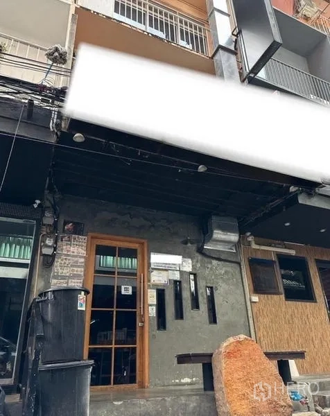 อาคารพาณิชย์ ให้เช่าหรือขายในWatthana, Bangkok - ด้านหน้าตึกแถวติดถนน ซุ้มประตูบานกระจก ผนังคอนกรีต และกันสาดสีดำพร้อมพื้นที่ติดป้าย