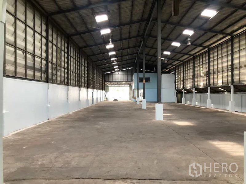 Warehouse for rent in Sai Noi, Nonthaburi - Long central aisle of the warehouse with ventilated side panels and high ceiling.