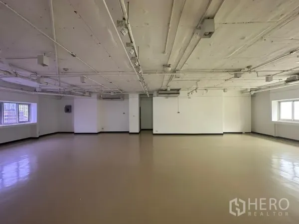办公空间 出租在Pathum Wan, Bangkok - 大型空置办公室内景，轨道照明、干净地面与双面采光窗。