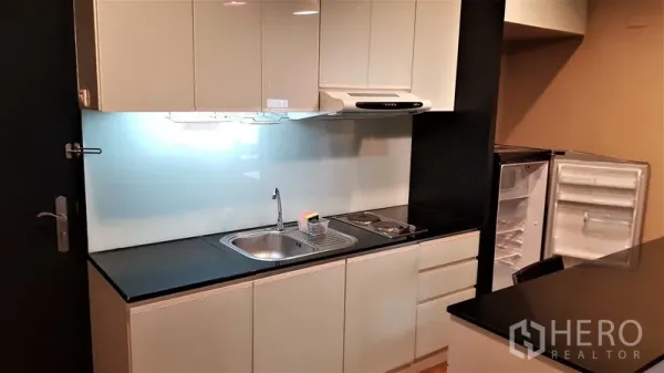 คอนโด ให้เช่าในRatchathewi, Bangkok - ครัวแพนทรีสมัยใหม่ ตู้สีขาวเงา ท็อปหินสีดำ เตา เครื่องดูดควัน อ่างล้างจาน และตู้เย็น