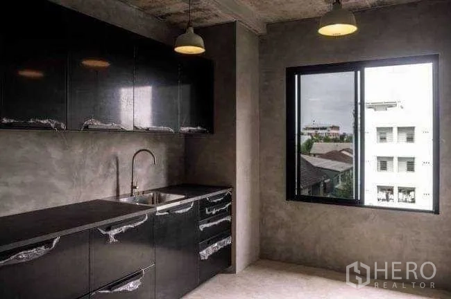 Office Space for rent or sale in Lak Si, Bangkok - Pantry with glossy black cabinets, sink, pendant lights, and a window view.