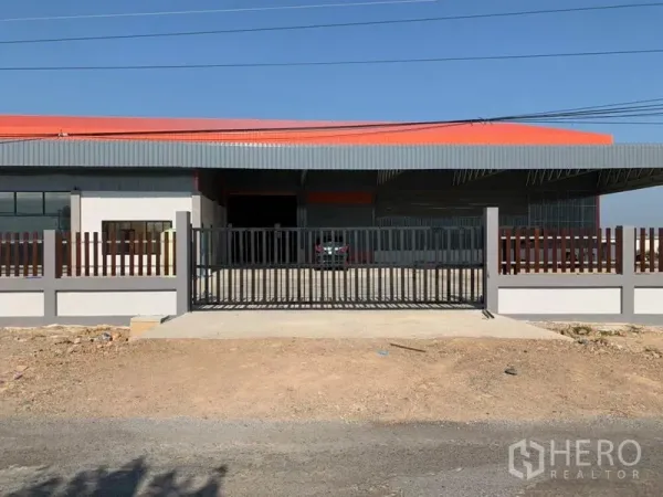 Warehouse for sale in Phra Nakhon Si Ayutthaya - Front gate and driveway of the fenced warehouse compound with a wide covered loading bay.