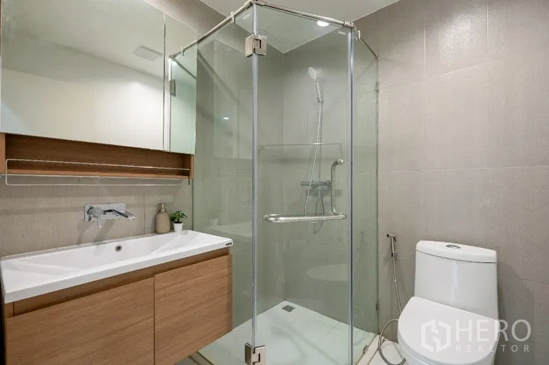 คอนโด ขาย - ห้องน้ำโมเดิร์น มีตู้กระจกกั้นอาบน้ำ อ่างล้างหน้าแบบติดผนัง และโถสุขภัณฑ์