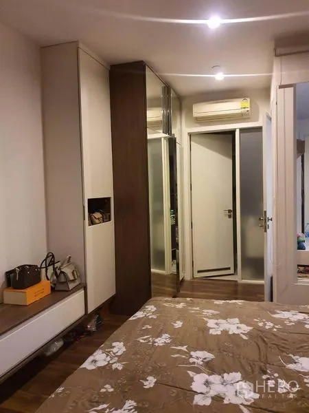 Condominium for sale in Bangkok - Bedroom corner showing mirrored wardrobe and a doorway to the bathroom.