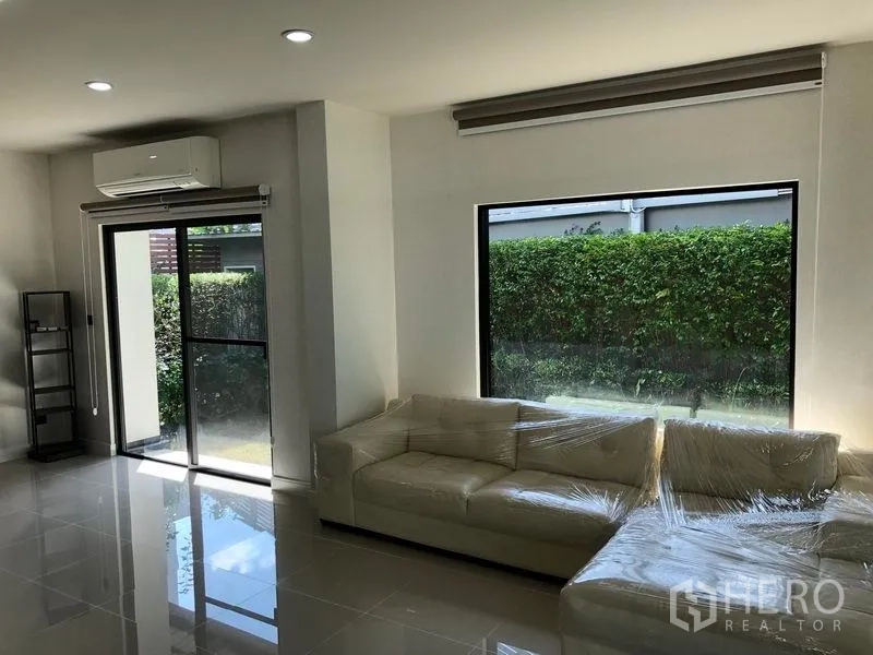 Detached House for rent in Bang Kapi, Bangkok - Living area with large windows, sliding door, air conditioning and cream sofas.