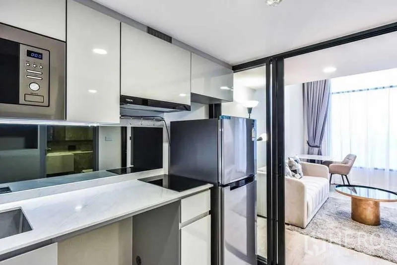 Condominium for rent in Huai Khwang, Bangkok - Close-up of sleek kitchenette with mirror backsplash and built-in appliances.