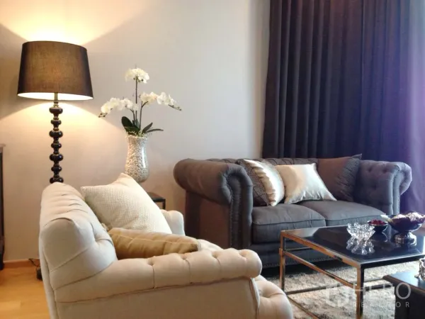 公寓 出租在Khlong Toei, Bangkok - 优雅客厅，切斯特菲尔德风沙发、落地灯、深色窗帘与玻璃茶几。