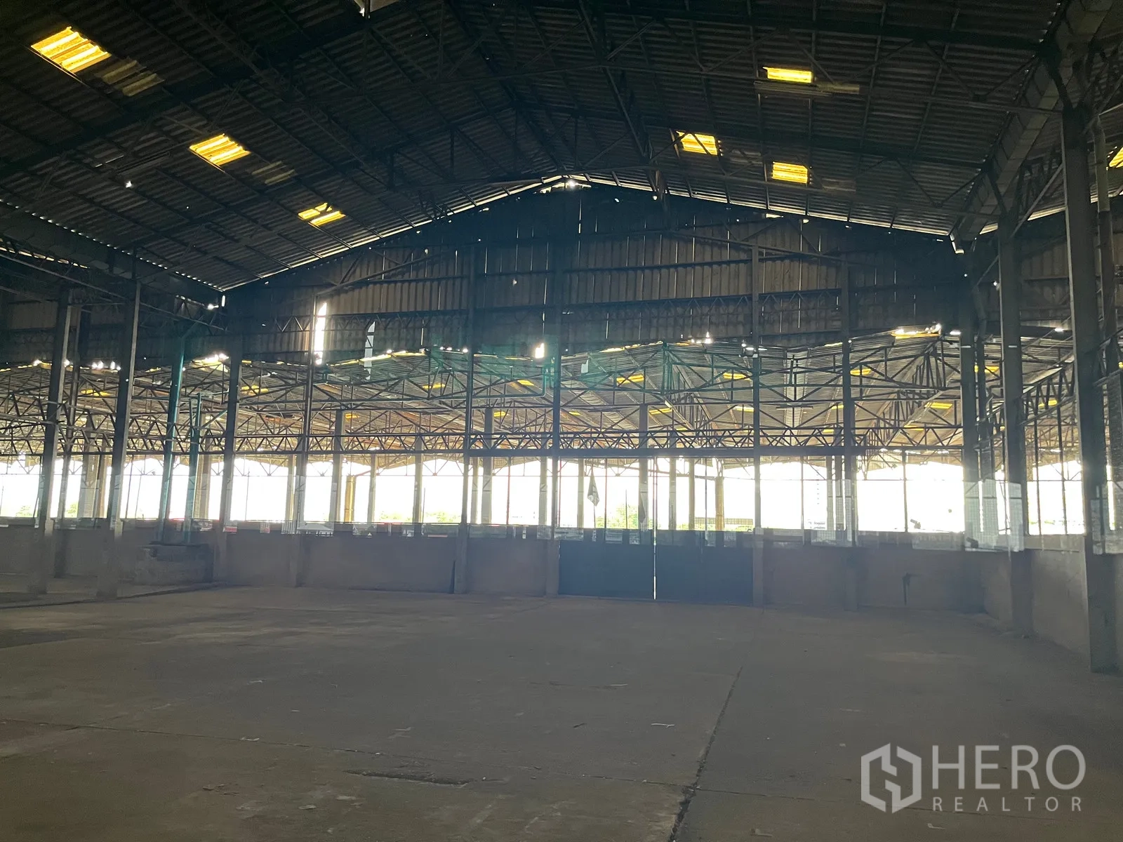 Warehouse for rent in Rat Burana, Bangkok - Large industrial space with high roof, perimeter walls, and bright natural light from tall openings.