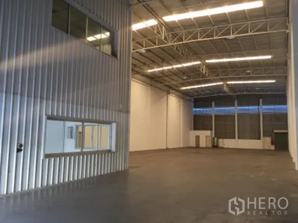 工厂 出租在Khlong Luang, Pathum Thani - 高挑仓库内部，钢结构屋顶、明亮灯带、平整地面与内嵌窗户。