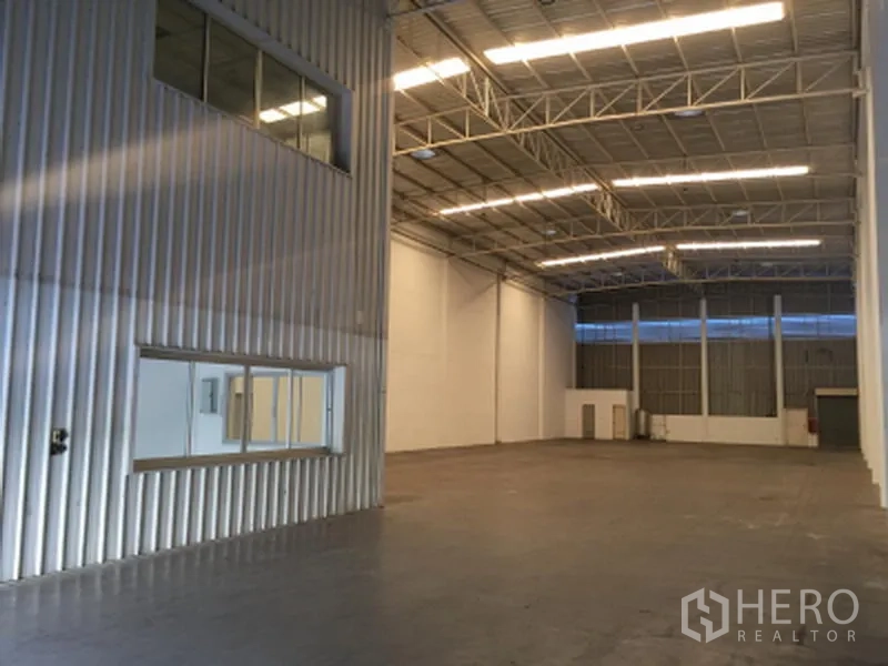 工厂 出租在Khlong Luang, Pathum Thani - 高挑仓库内部，钢结构屋顶、明亮灯带、平整地面与内嵌窗户。
