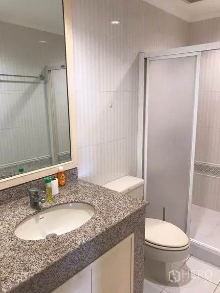 Condominium for rent in Sathon, Bangkok - Bathroom with granite vanity, toilet and glass-enclosed shower.