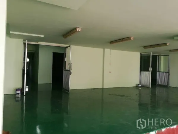 Factory for rent in Mueang Samut Sakhon, Samut Sakhon - Ground-floor workspace with multiple glass-and-metal doors and fluorescent lighting.