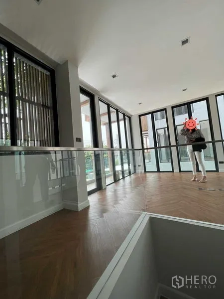 Home Office for sale in Wang Thonglang, Bangkok - Open workspace with floor-to-ceiling sliding doors, glass balustrade and wood floors.