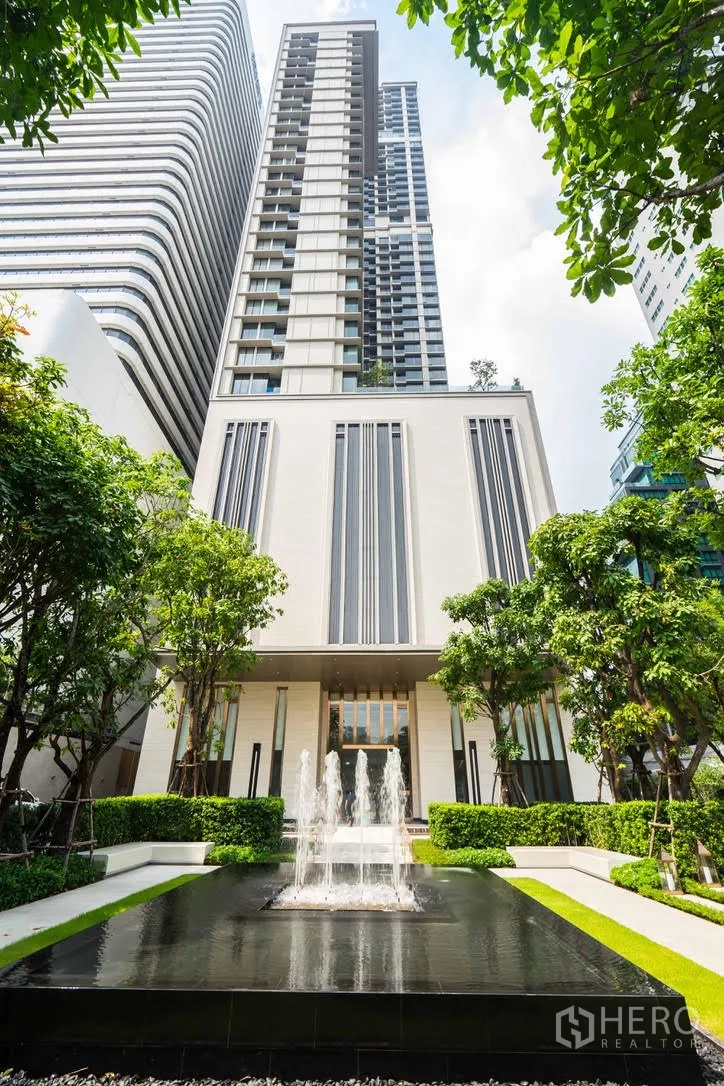 Condominium for rent in Watthana, Bangkok - High-rise condominium exterior with landscaped entrance and water feature.