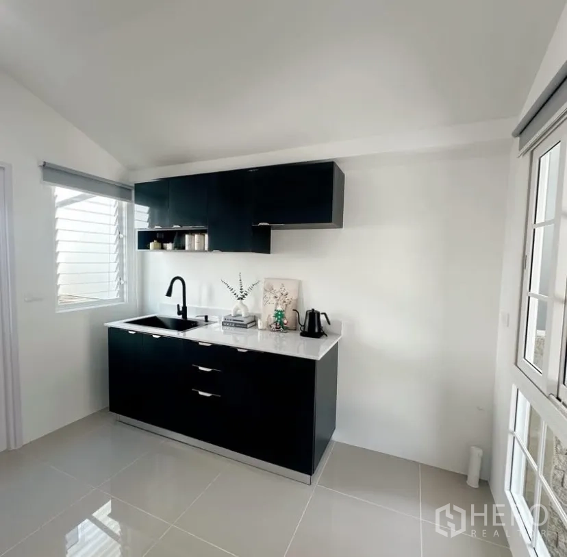 บ้าน ให้เช่าในMueang Samut Prakan, Samut Prakan - ห้องครัวบิวท์อิน ตู้สีดำ เคาน์เตอร์ขาว อ่างล้างจาน และหน้าต่าง