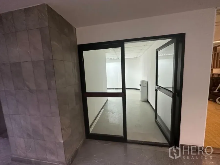 办公空间 出租在Khlong Toei, Bangkok - 走廊侧玻璃门办公入口，旁有石质墙面