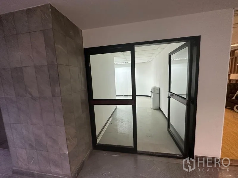 办公空间 出租在Khlong Toei, Bangkok - 走廊侧玻璃门办公入口，旁有石质墙面