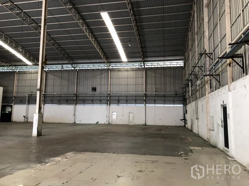 工厂 出租在Phra Nakhon Si Ayutthaya - 厂房一隅，高墙体、管线桥架、夹层走道与承重立柱清晰可见。