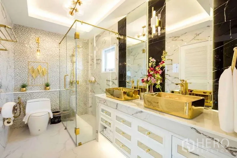联排别墅 出租在Lat Phrao, Bangkok - 大理石浴室，玻璃淋浴间与双金色洗手盆及黄铜配件。