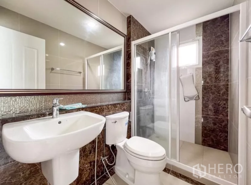 独立式住宅 出租在Chom Thong, Bangkok - 楼上卫生间，大镜面与玻璃淋浴房，中性色墙面。