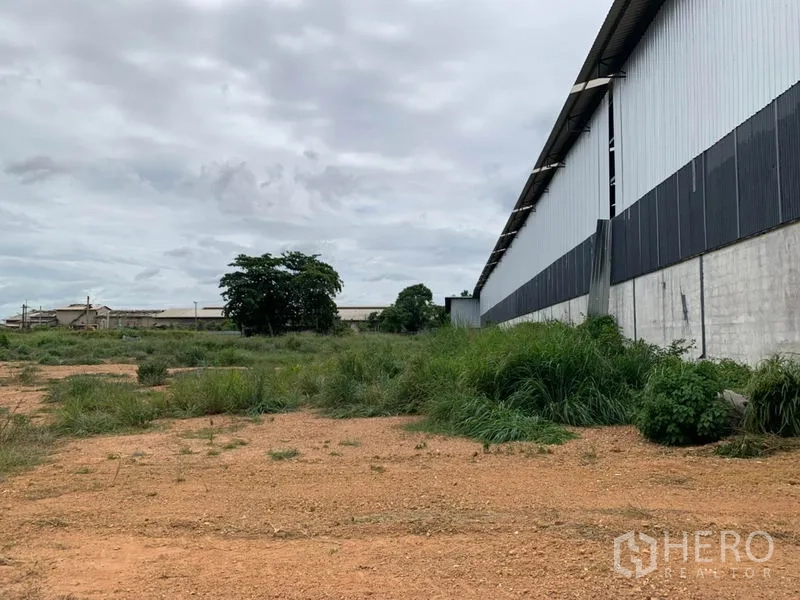 โรงงาน ให้เช่าในChon Buri - ที่ดินว่างข้างอาคาร พื้นหินคลุกและหญ้า เหมาะสำหรับจอดรถบรรทุกหรือขยายอาคาร