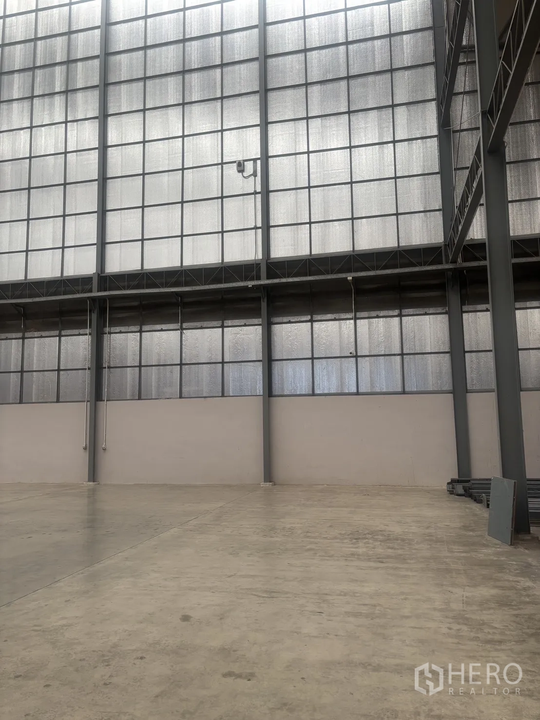 Warehouse for rent in Mueang Samut Sakhon, Samut Sakhon - Interior of a large warehouse with very high ceiling, steel frame walls and smooth concrete floor.