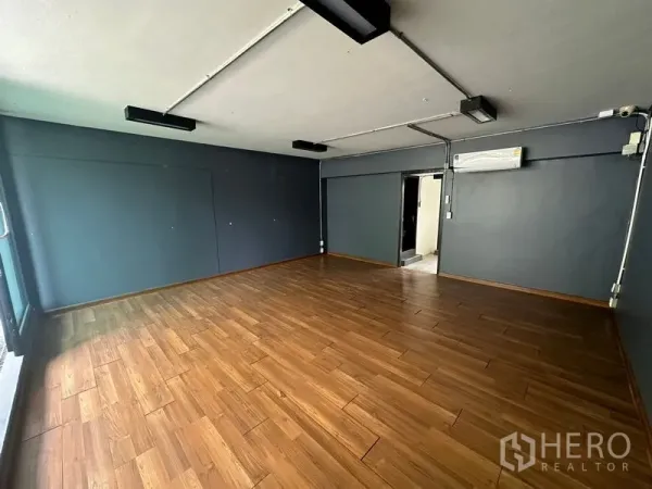 Home Office for rent in Phra Khanong, Bangkok - Ground-floor room with wood flooring, dark accent walls and ceiling lights.