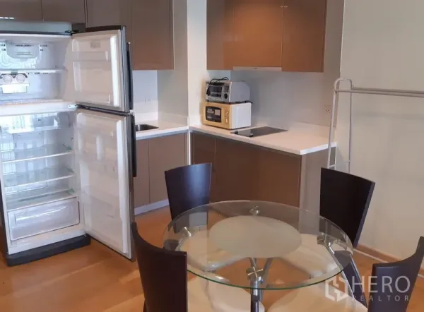 คอนโด ให้เช่าในKhlong Toei, Bangkok - ครัวบิลท์อินโทนสีน้ำตาล ตู้เย็นเปิดอยู่ พร้อมโต๊ะรับประทานอาหารกระจกทรงกลม