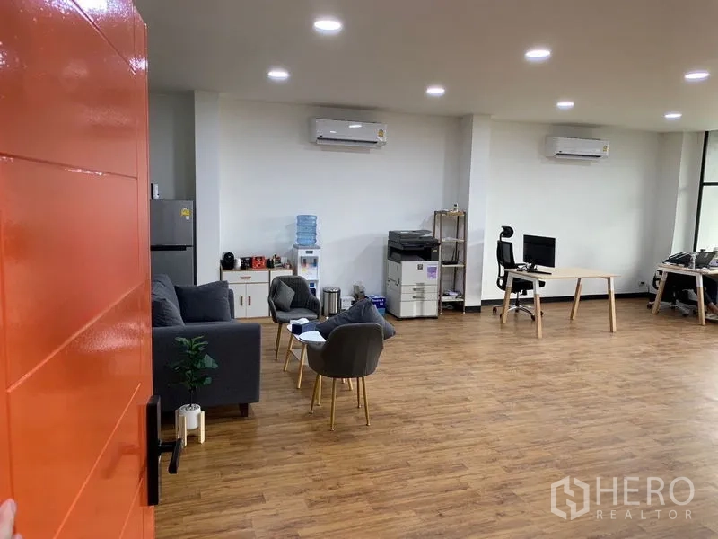 Office Space for rent in Khlong Toei, Bangkok - Open-plan office with wood floors, lounge seating, pantry and printer area, bright LED lights and wall AC units.