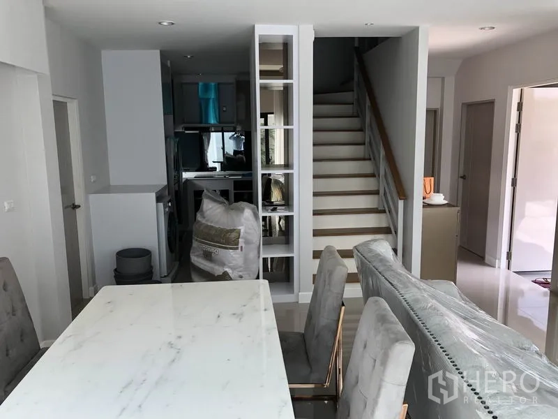 独立式住宅 出租在Prawet, Bangkok - 开放式餐区，大理石餐桌，面对楼梯与内置书架。