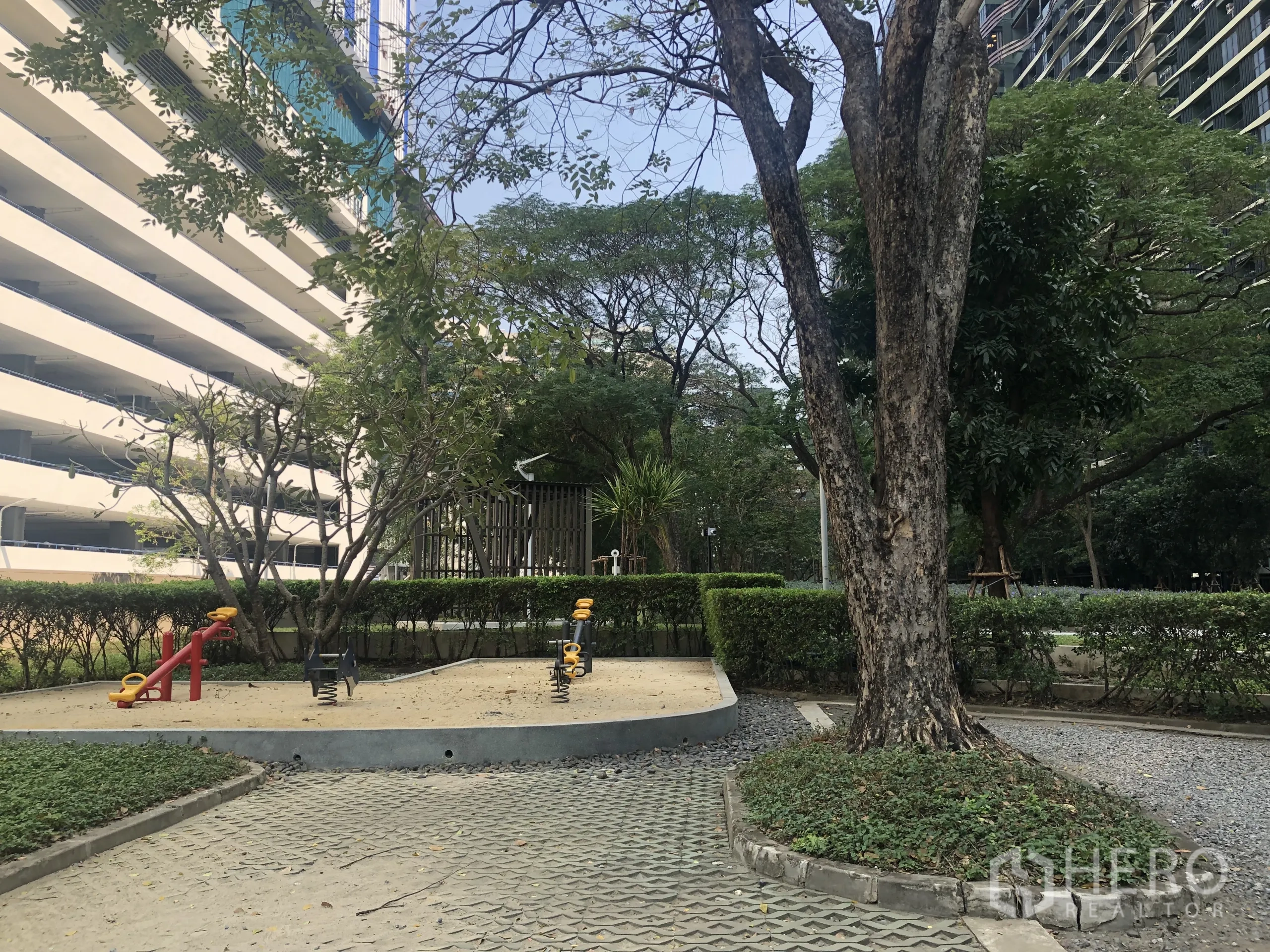 Condominium for sale in Chatuchak, Bangkok - Children’s playground with spring riders set amid trees and hedges in the condo grounds.