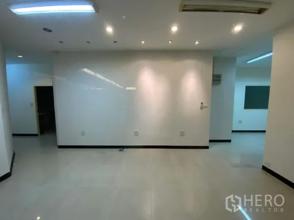Office Space for rent in Watthana, Bangkok - Open-plan workspace featuring a spotlit white wall and large tiled flooring.