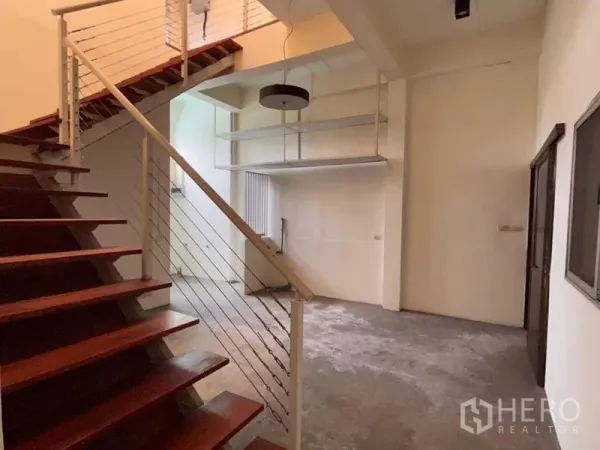 Warehouse for rent in Bang Phli, Samut Prakan - Open workspace with wooden staircase and metal railings under a high ceiling with suspended shelves.