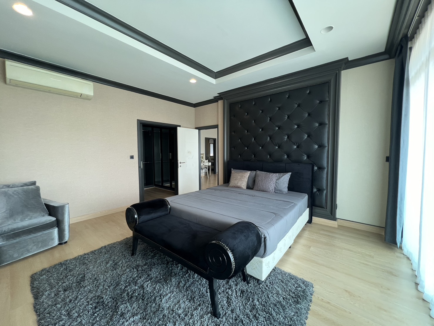 Detached House for rent in Bang Kapi, Bangkok - Master bedroom with tufted headboard, bench seat and large rug.