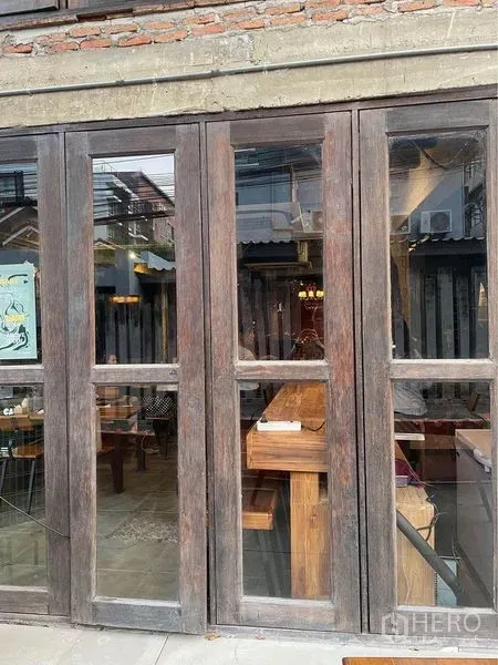 零售空间 出租在Phaya Thai, Bangkok - 临街玻璃木框门面，高挑落地门展示温馨室内与吧台。